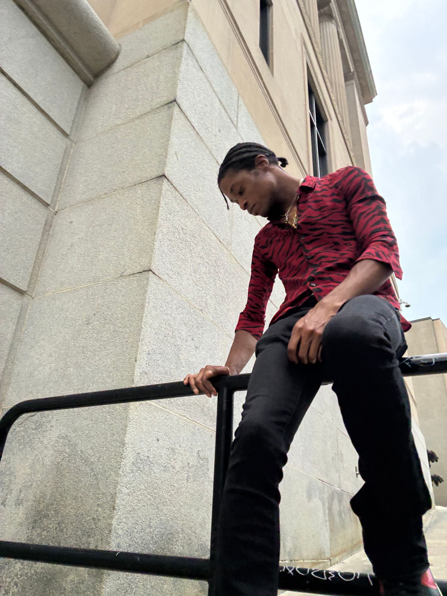 GXDLYJ in a red tiger-stripe shirt on a stone building rail