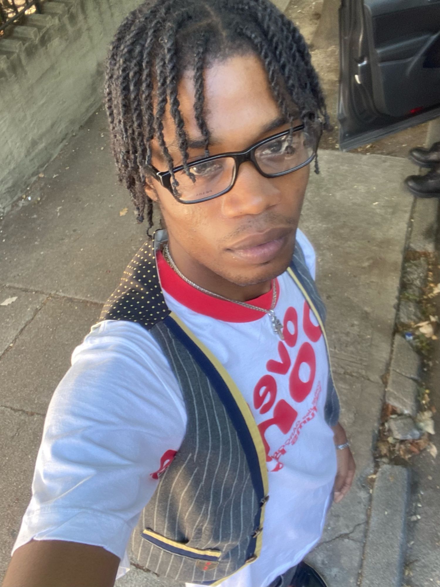 Self portrait: twists, glasses, pinstripe vest over a graphic tee